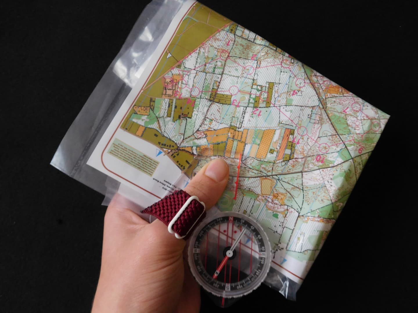 A thumb compass positioned on a printed navigation map
